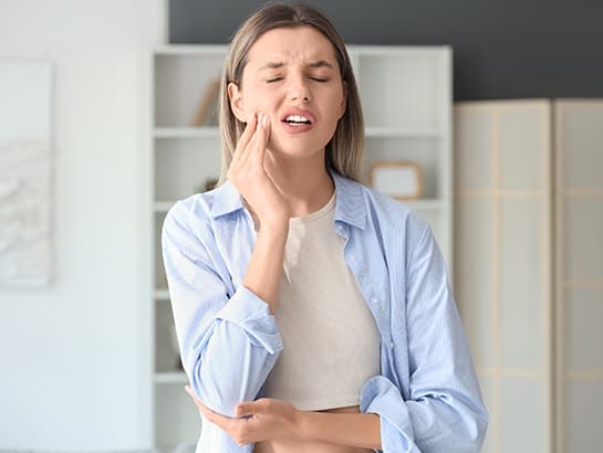 A woman experiencing sudden tooth pain, the kind of dental emergency Sauga Smiles Dental treats same-day