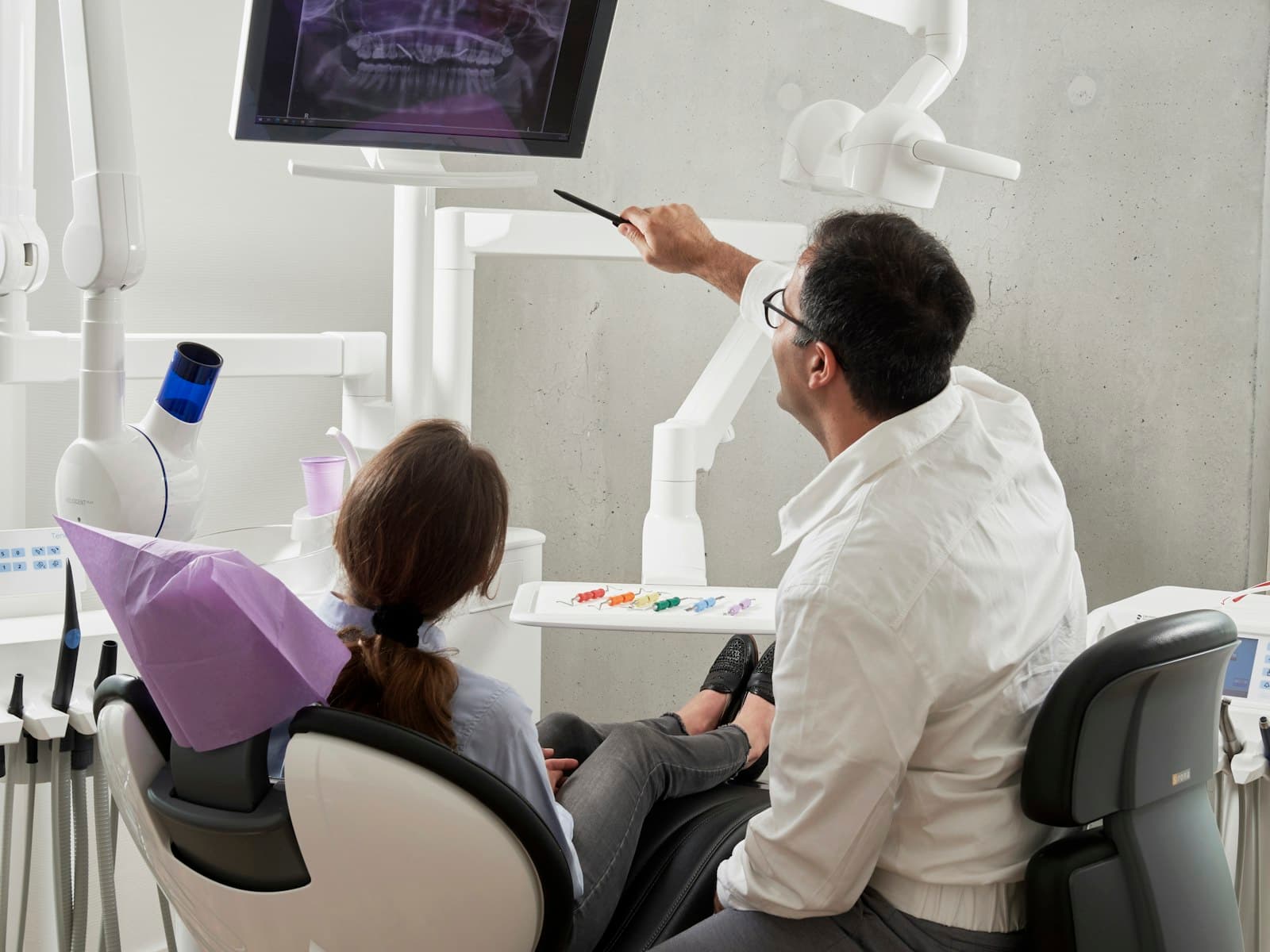 A dentist reviewing a patient's dental X-ray on a chairside screen